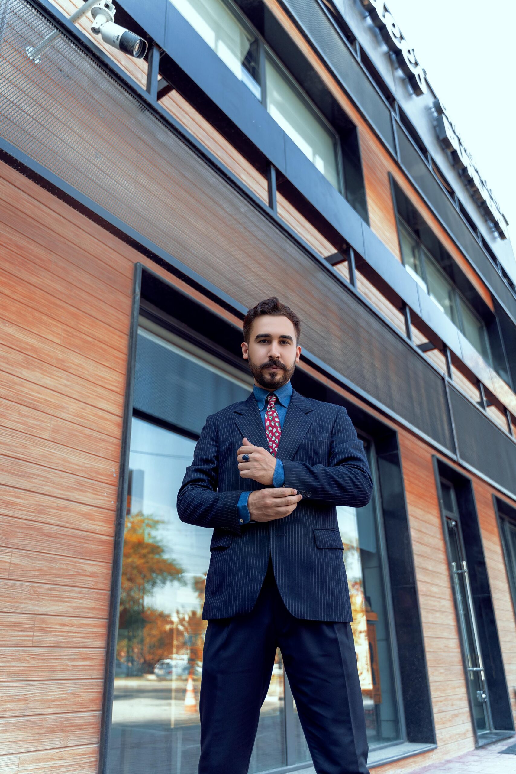 Low-angle shot of a businessman in a suit outside a modern office building.